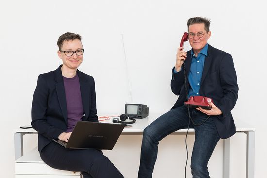 Bettina Enzenhofer and Marjo Rauhala with laptop and landline phone