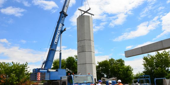 [Translate to English:] Die hohlen Beton-Doppelwandelemente werden mit Hilfe eines Krans exakt aufeinander gestapelt und dann vor Ort mit Beton ausgegossen.
