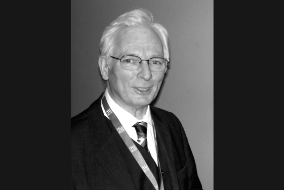 Porträtbild von Prof. Springer in Schwarz-Weiß. Er hat weiße kurze Haare und trägt ein Jackett mit weißem Hemd.