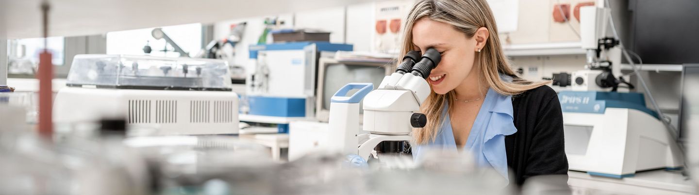 Forscherin im Labor blickt in Mikroskop 