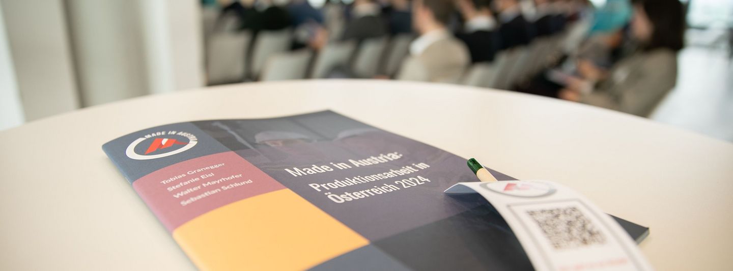 im Hintergrund Menschen sitzend, im Vordergrund Tisch mit Made in Austria Programm