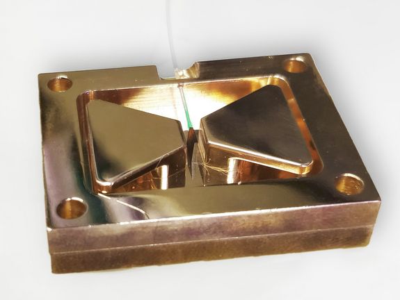 Der Mikrowellen-Resonator (Kupfer) mit dem Diamanten in der Mitte. Die speziellen Defekte bestehend aus Stickstoff und fehlendem Atom leuchten leicht rot, wenn sie mit grünem Licht aus der Glasfaser angestrahlt werden.