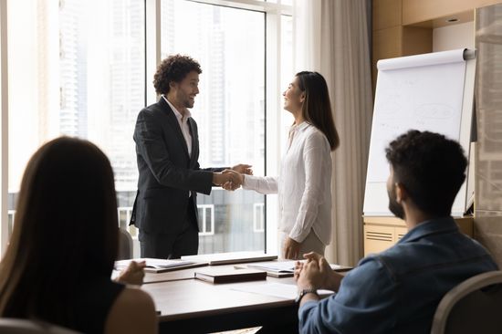 A team sits together at a table and welcomes a new colleague.