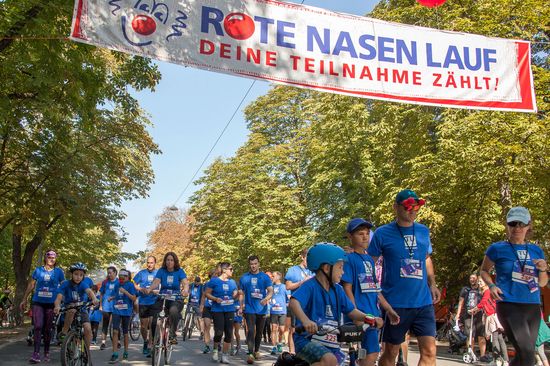 Teilnehmer_innen am ROTE NASEN LAUF mit TU-T-Shirt, laufend und auf Fahrrädern.