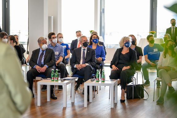 Antonio Guterres, Alexander Van der Bellen und Rektorin Sabine Seidler sitzen im Publikum und hören den Vorträgen zu.