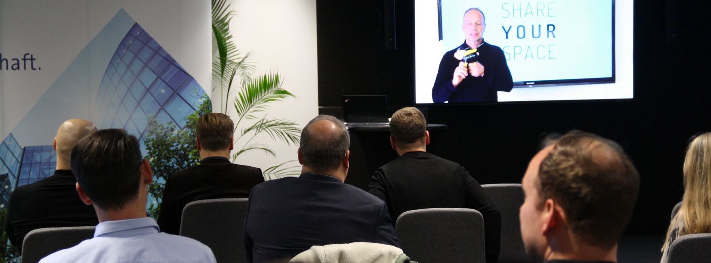 Die Innovation Challenge 2021 aus der Perspektive hinter dem Publikum während vorne ein Vortrag läuft.