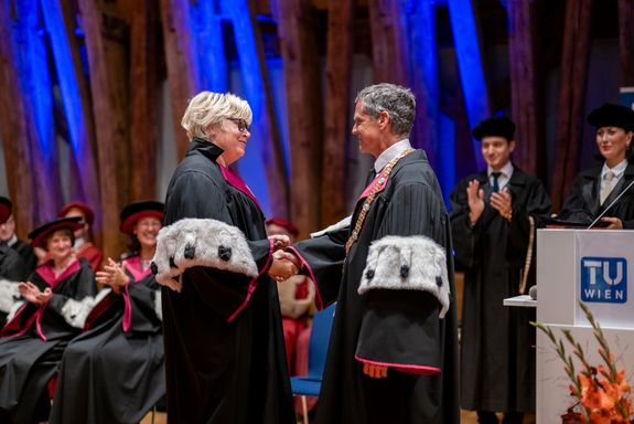 Sabine Seidler und Jens Schneider geben einander die Hand. Dahinter sind weitere Personen zu sehen, die applaudieren