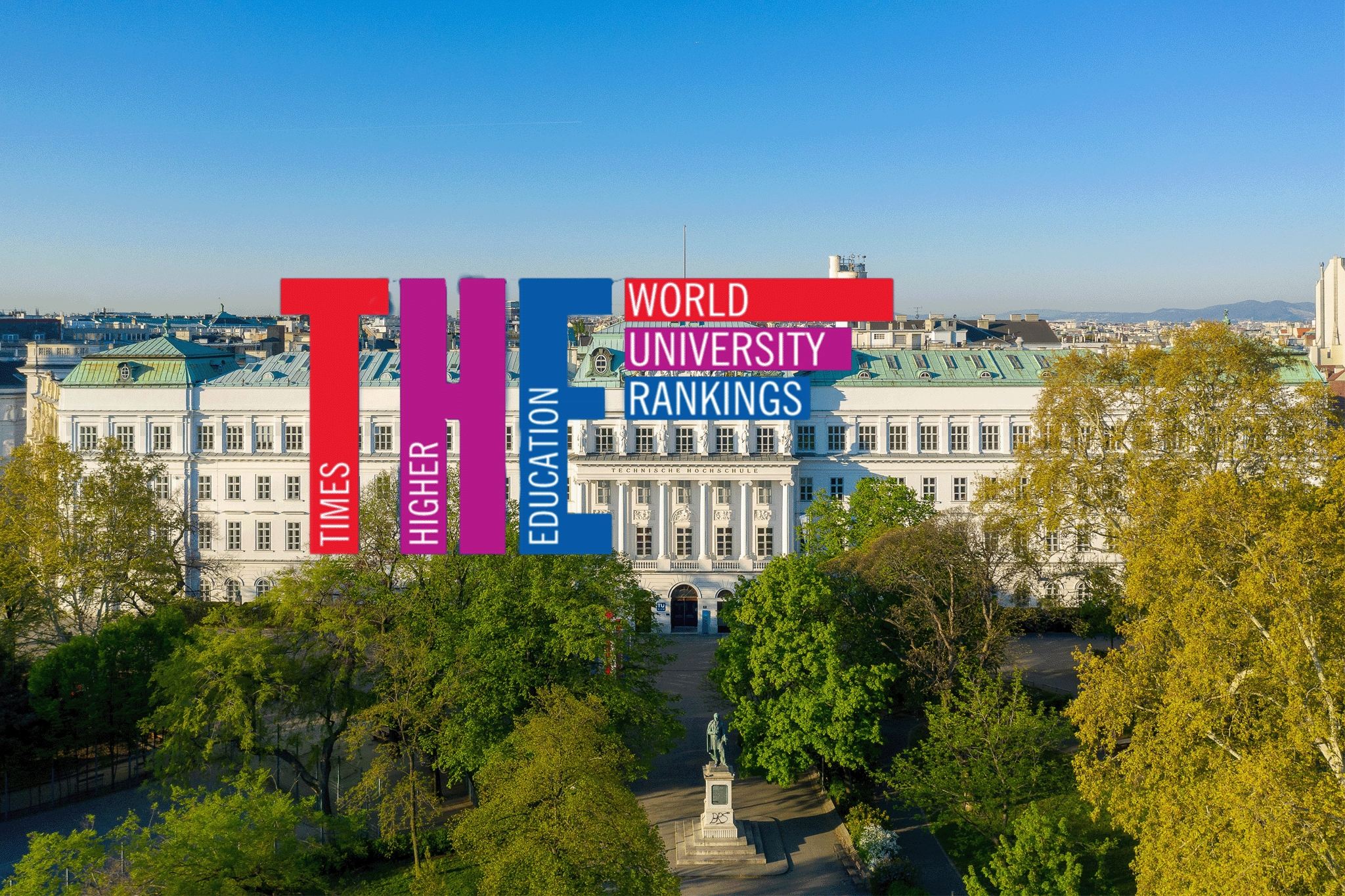 Drohnenansicht TU Wien, im Vordergrund der Resselpark, darüber der THE-Schriftzug in Rot, Violett, Blau.