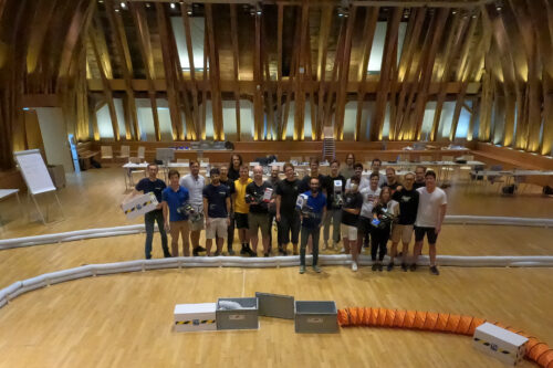 Group picture of students, guests with racing cars on the race track