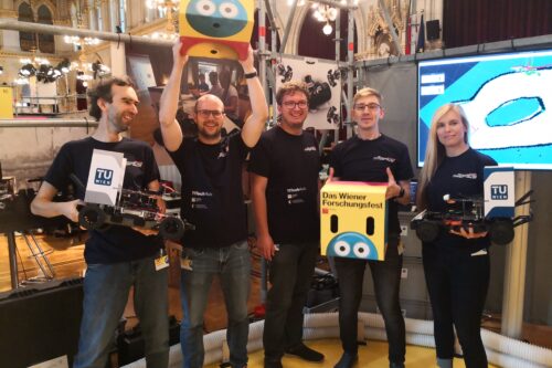 Group picture of students at Forschungsfest with two racing cars