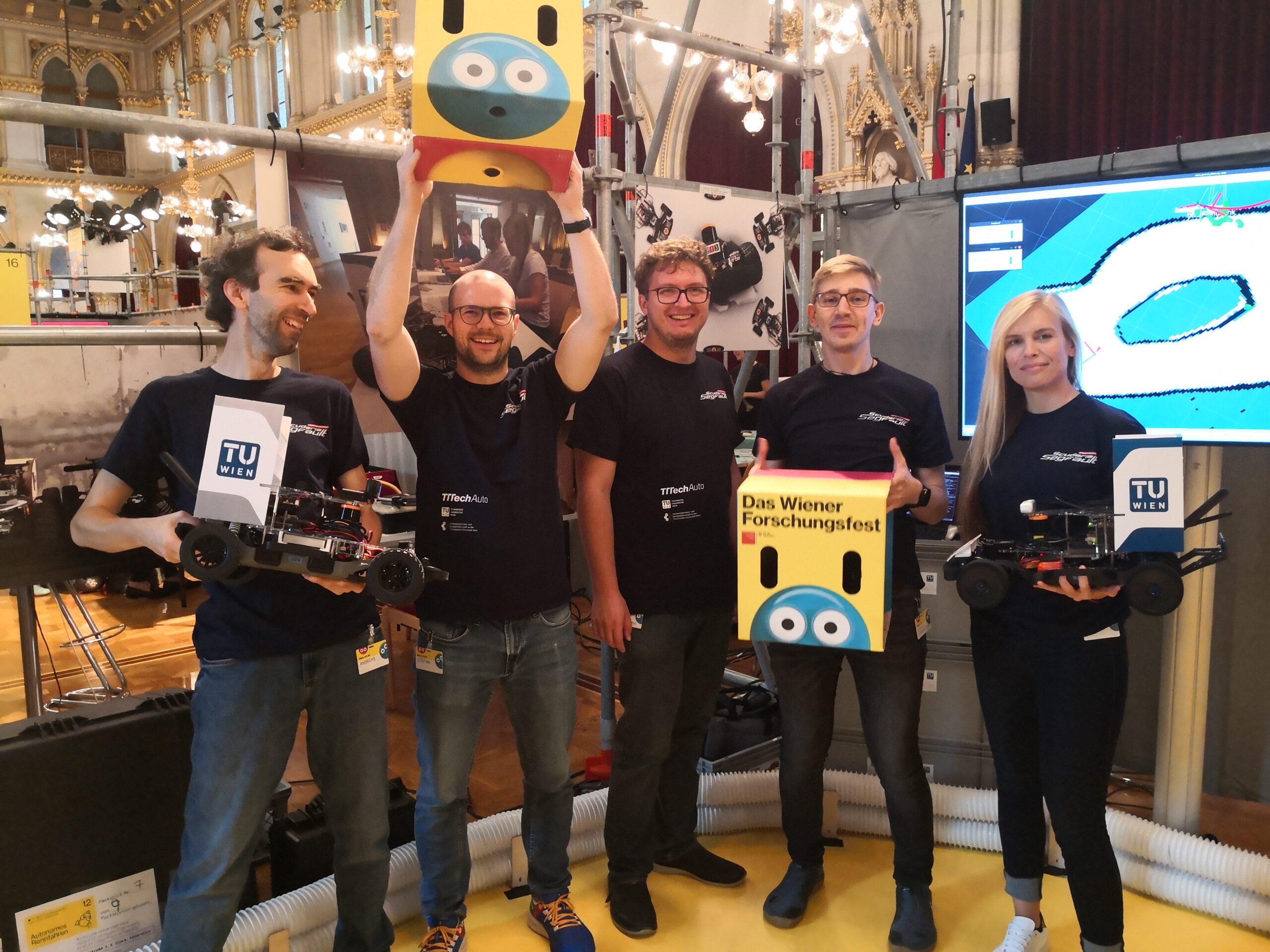 Group picture of students at Forschungsfest with two racing cars