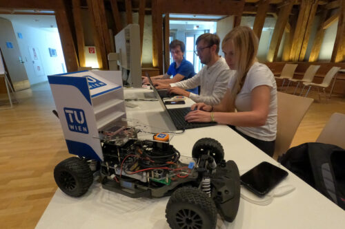 Students working on notebook with race car