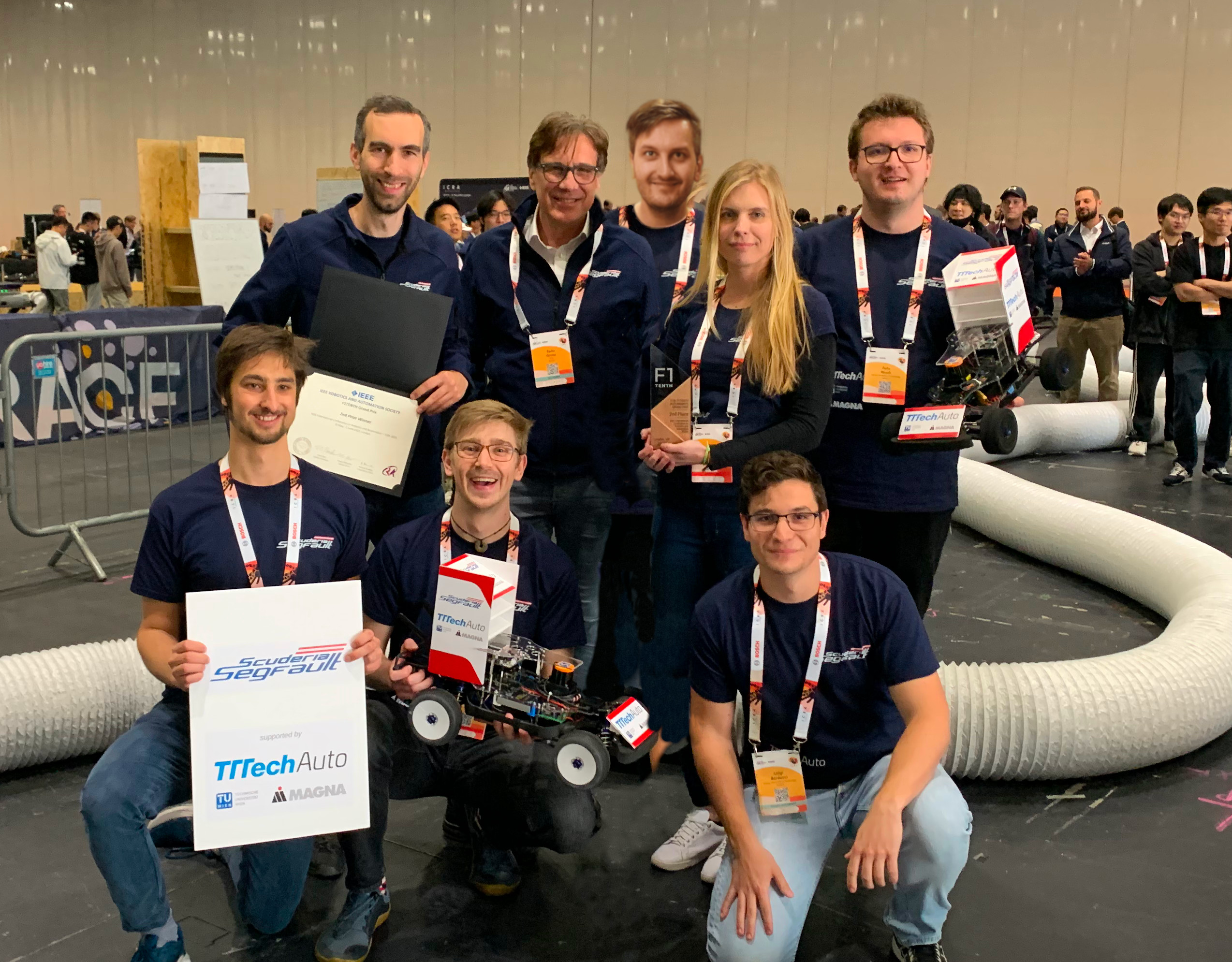 Group picture of the team with cars and trophy