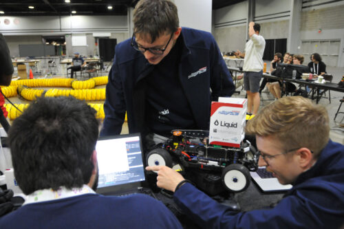 Team members are preparing the model race car and the software