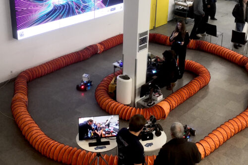 Racing car on the track on the ground with people looking at it.