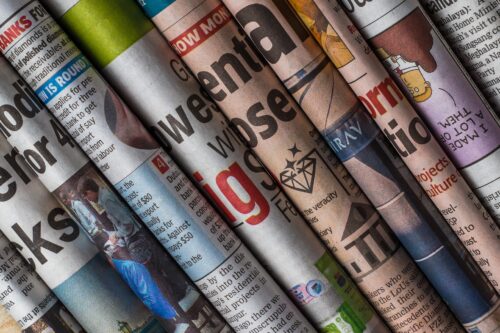 A horizontally arranged stack of different newspapers