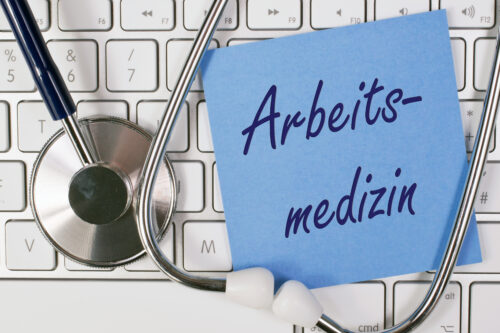 A postit on a keyboard with the inscription "Arbeitsmedizin"