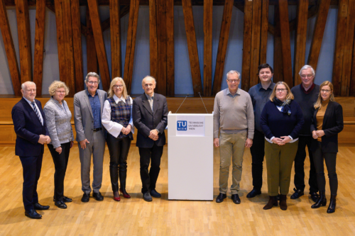 Gruppenfoto Quality Audit im Kuppelsaal der Tu Wien; mittig ein weißes Pult, daneben rechts und links je 5 Personen stehend