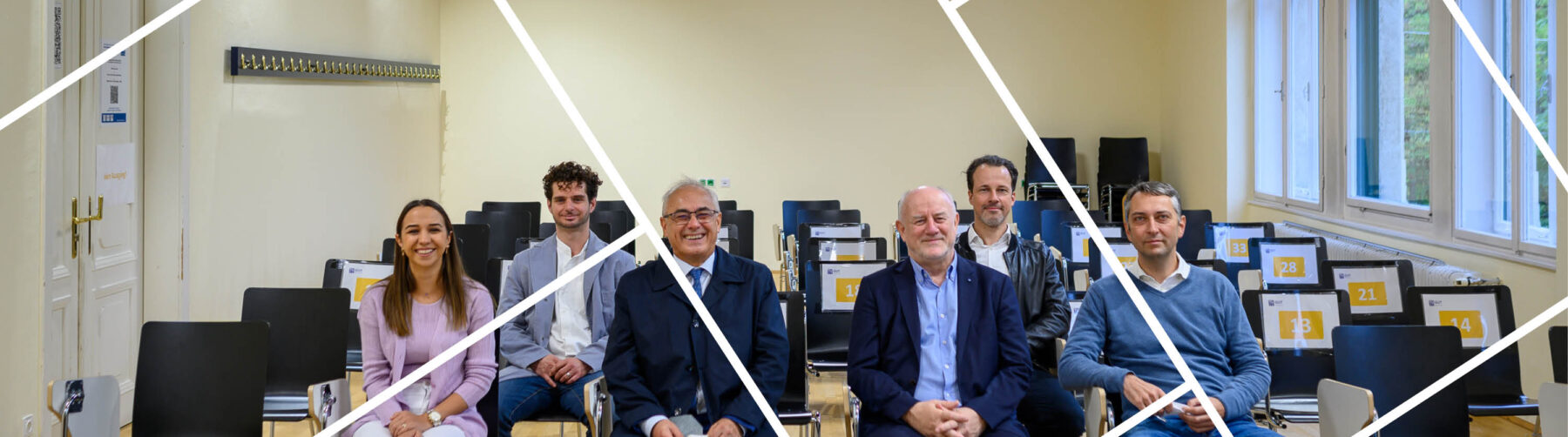 Headerbild mit Gitternetzlinien Innenaufnahme Institut Managementwissenschaften Gruppe sitzend: von links: Nurcan Coskun, Konstantinos Xynogalas, Amtsdir. Hodecek, VR Eberhardsteiner, Jürgen Fränzer und Prof. Schlund