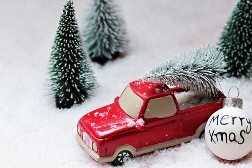 Symbolbild Spielzeugauto mit Weihnachtsbaum am Dach im Schnee