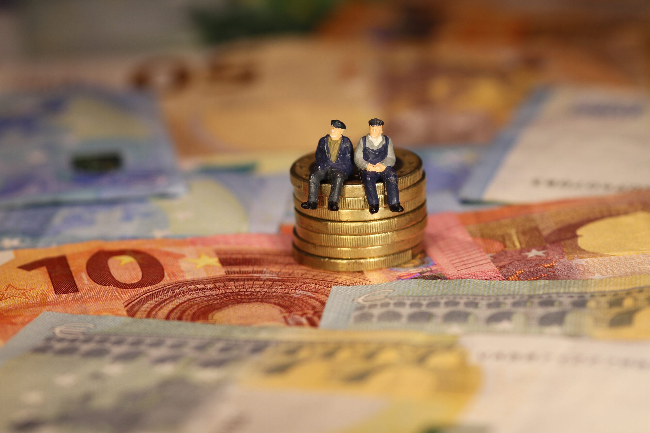 Zwei Figuren, die auf einem Stapel von 1 Euro-Münzen sitzen